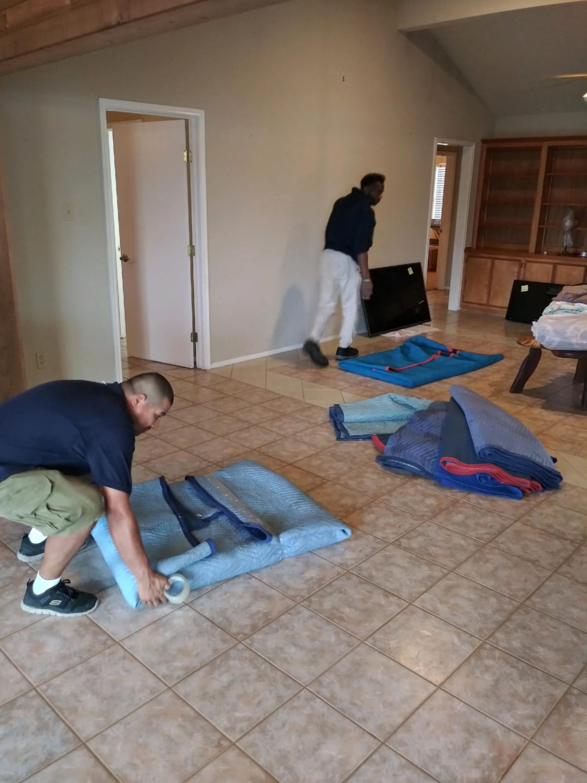 Two men are moving a mattress in the floor.